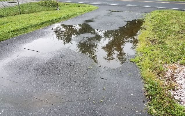 Pitching the asphalt toward the center of the driveway and install a drain at the low point can prevent water from accumulating in one area and damaging the driveway