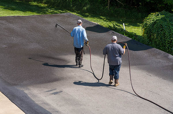 Workers spraying blacktop or asphalt sealer onto roadway Workers spraying blacktop or asphalt sealer onto roadway